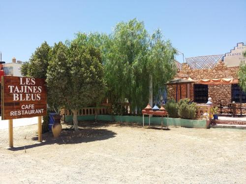 a sign in front of a building with a tree and a store at Les Tajines Bleus in Tamanar