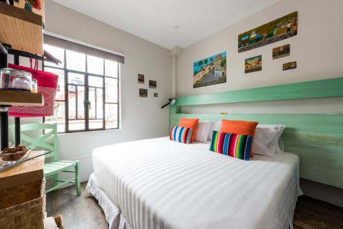 a bedroom with a large white bed with colorful pillows at La Palomilla Bed & Breakfast in Mexico City
