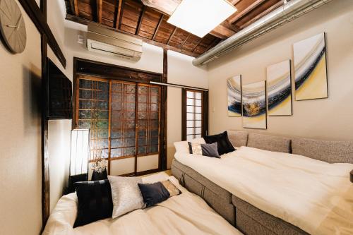 een woonkamer met twee bedden en een bank bij Prestige Suites Osaka Teradacho in Osaka