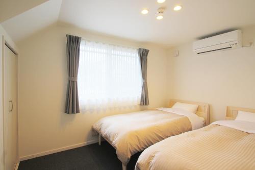 Duas camas num quarto com uma janela em Villas Waraku em Fujiyoshida