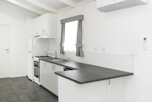 a white kitchen with a sink and a stove at Anchor Belle Holiday Park in Cowes