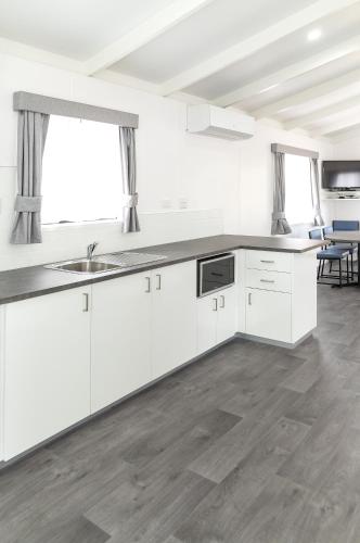 an empty kitchen with white cabinets and a sink at Anchor Belle Holiday Park in Cowes