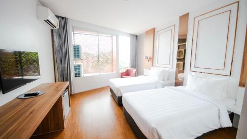a hotel room with two beds and a desk at แจสเปอร์โฮเทล Jasper Hotel in Ban Phai
