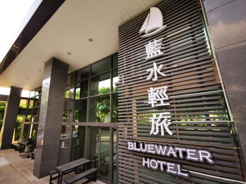 a building with a sign for a hotel at Bluewater Hotel Xpark Gloria Outlets Taoyuan Baseball Stadium in Dayuan
