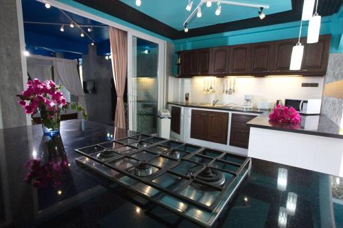 a kitchen with a stove and a counter with purple flowers at Baan Heaven / Patong Beach Pool Villa Sleeps up to 15 in Patong Beach