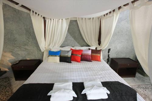 a bedroom with a canopy bed with colorful pillows at Baan Heaven / Patong Beach Pool Villa Sleeps up to 15 in Patong Beach