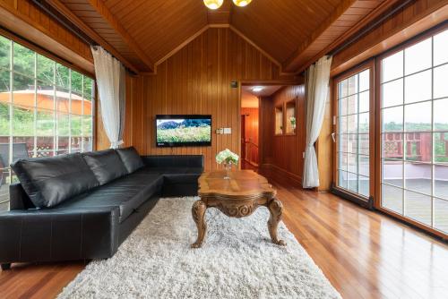 a living room with a black leather couch and a table at The Hyu Largo in Yongin