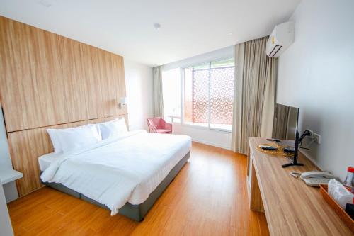 a bedroom with a bed and a desk and a television at แจสเปอร์โฮเทล Jasper Hotel in Ban Phai
