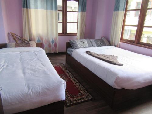two beds in a room with purple walls and windows at STUPA VIEW INN in Kathmandu
