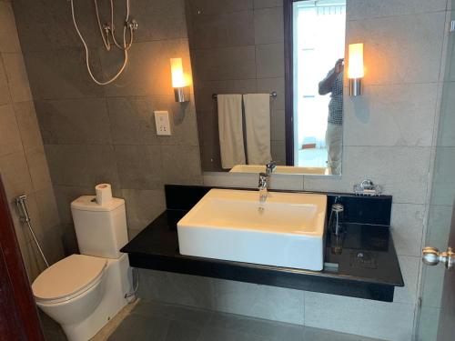 a bathroom with a sink and a toilet and a mirror at 123 Ocean Front Condo in Nilaveli
