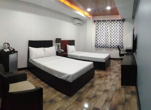 a bedroom with two beds and a couch and a chair at Hotel Gabriella in Tagbilaran City