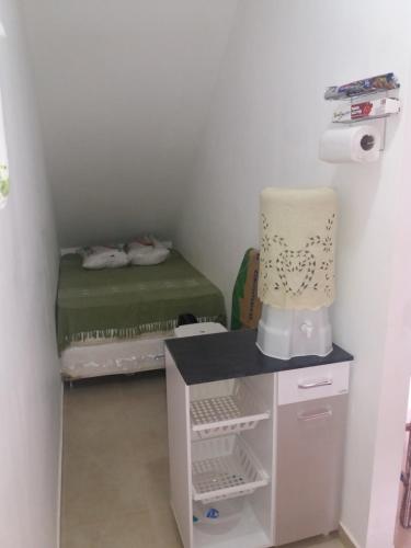 a small room with a bed and a table with a lamp at Apartamento 05 Vivendas do Serrano - Lençóis in Lençóis