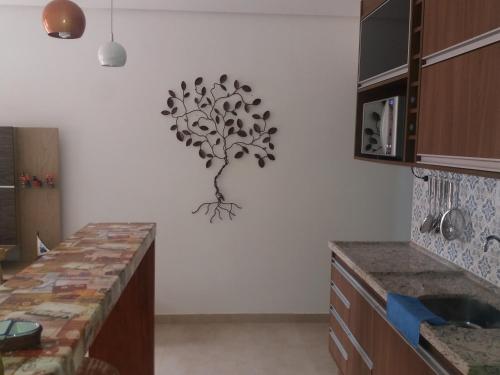 a kitchen with a tree wall art on the wall at Apartamento 05 Vivendas do Serrano - Lençóis in Lençóis