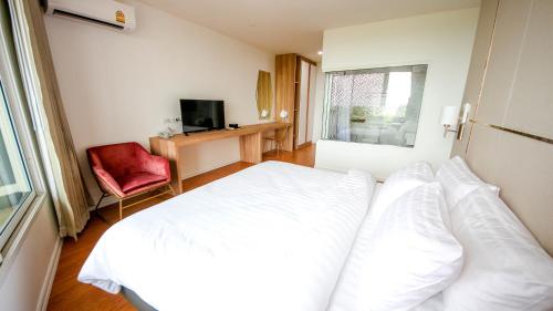 a bedroom with a white bed and a red chair at แจสเปอร์โฮเทล Jasper Hotel in Ban Phai