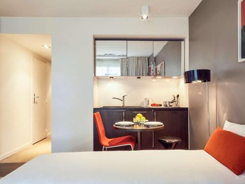 a bedroom with a bed and a table and a kitchen at Adagio Nice Centre in Nice