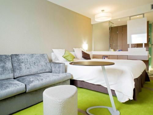 a room with a bed and a couch and a table at ibis Styles Bordeaux Aéroport in Mérignac