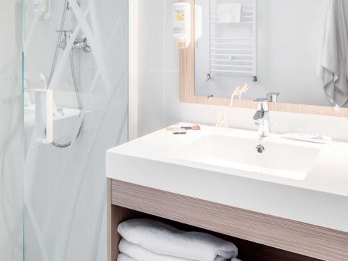 a bathroom with a white sink and a shower at Aparthotel Adagio Access Paris Clichy in Clichy