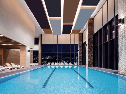 a swimming pool in a hotel with white chairs at Grand Mercure Ambassador Hotel and Residences Seoul Yongsan in Seoul