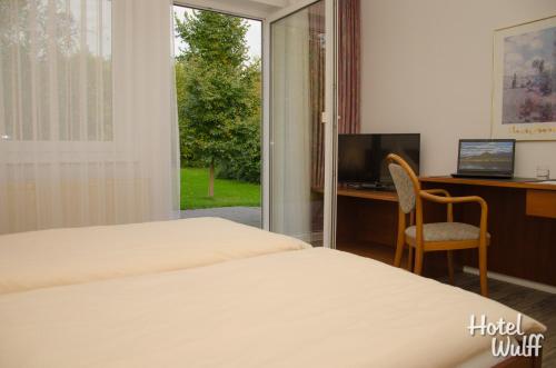 1 dormitorio con cama, escritorio y ventana en Hotel Wulff, en Warburg