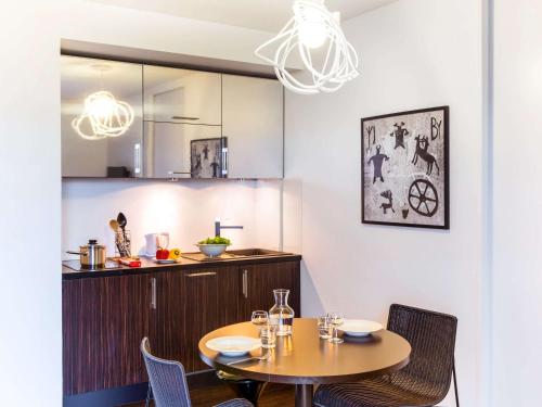 a dining room with a table and chairs and a kitchen at Adagio Nice Centre in Nice