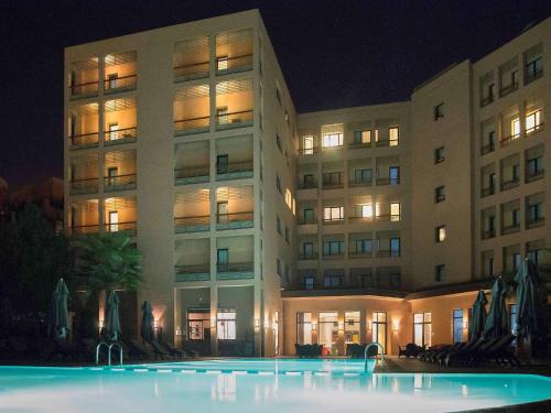 a building with a pool in front of it at night at Novotel Marrakech Hivernage in Marrakech