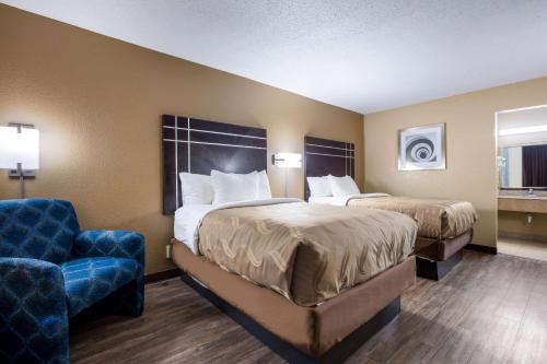 a hotel room with two beds and a chair at Quality Inn in Starkville