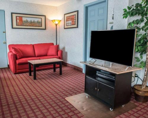 a living room with a red couch and a flat screen tv at Quality Inn & Suites North Gibsonia in Gibsonia