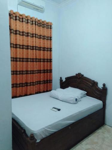 a bed with a wooden frame and a curtain at Wisma Kahyangan in Baubau