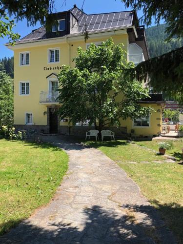 a large yellow house with a tree in front of it at Hotel Lindenhof in Bad Gastein