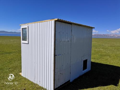 a white building in the middle of a field at Yurt Camp Ali-Nur, Lake Song-Kul , Kyrgyzstan, Юрточный лагерь Али Нур, на берегу озера Сон Кол in Naryn