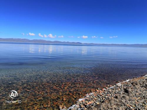 a large body of water with rocks in the water at Yurt Camp Ali-Nur, Lake Song-Kul , Kyrgyzstan, Юрточный лагерь Али Нур, на берегу озера Сон Кол in Naryn