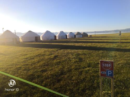 a stop sign in front of a field with tents at Yurt Camp Ali-Nur, Lake Song-Kul , Kyrgyzstan, Юрточный лагерь Али Нур, на берегу озера Сон Кол in Naryn