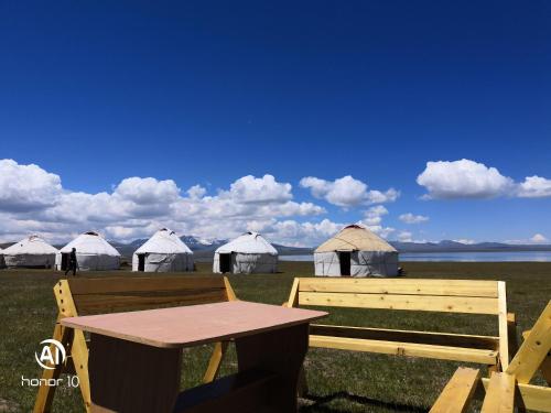 a wooden bench and a table and some tents at Yurt Camp Ali-Nur, Lake Song-Kul , Kyrgyzstan, Юрточный лагерь Али Нур, на берегу озера Сон Кол in Naryn