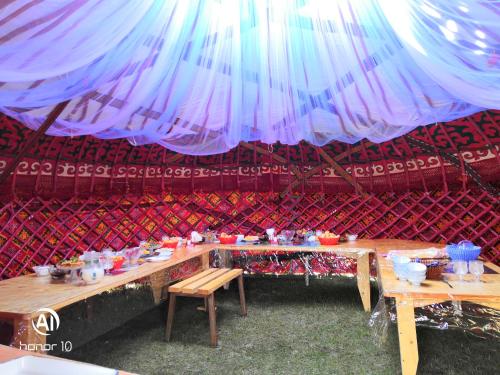 a tent with two tables with food on it at Yurt Camp Ali-Nur, Lake Song-Kul , Kyrgyzstan, Юрточный лагерь Али Нур, на берегу озера Сон Кол in Naryn