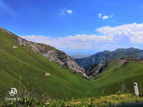 a green valley with mountains in the background at Yurt Camp Ali-Nur, Lake Song-Kul , Kyrgyzstan, Юрточный лагерь Али Нур, на берегу озера Сон Кол in Naryn