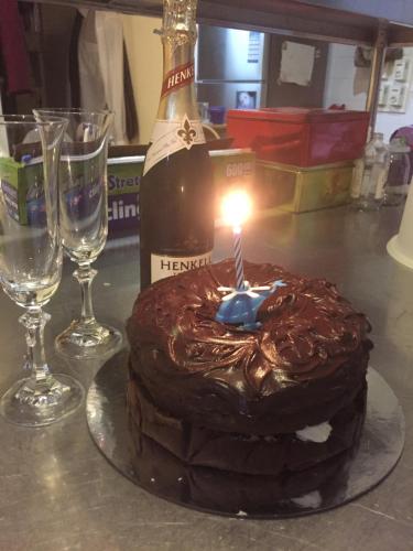 a chocolate cake with a candle and a bottle of wine at Oaktree Guest House in Narbethong