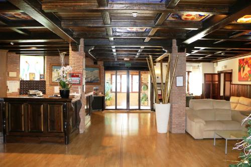 a living room with wooden ceilings and a couch and tables at Hotel El Guerra in Güéjar-Sierra