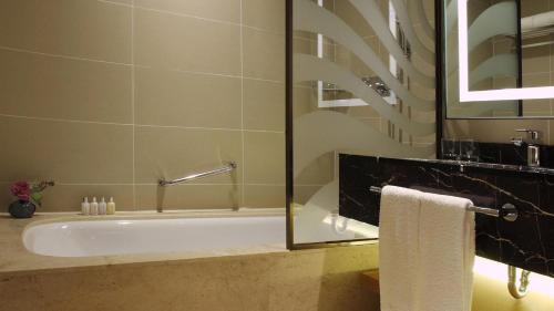a bathroom with a bath tub with a glass door at Lotte City Hotel Jeju Airport in Jeju