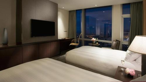 a hotel room with two beds and a flat screen tv at Lotte City Hotel Jeju Airport in Jeju