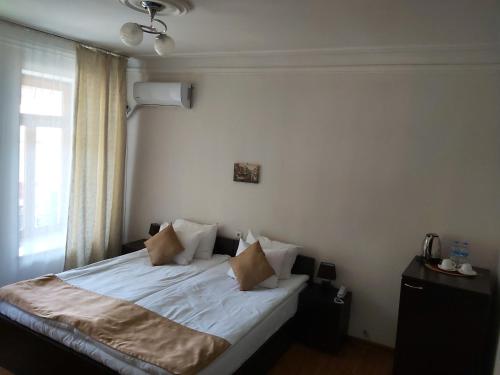 a bedroom with a bed with white sheets and pillows at Hotel Nata in Tbilisi City