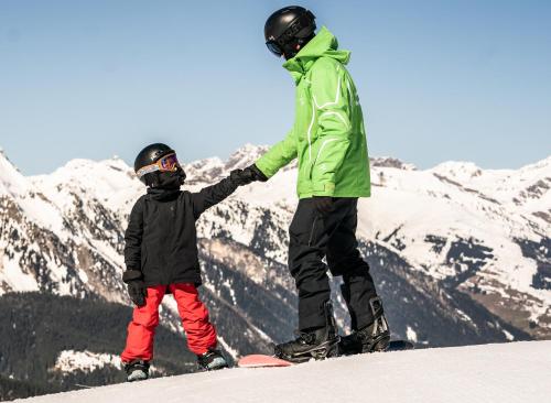 a man and a child on a snowboard on a mountain at edelweiss lounge restaurant hotel pizza cafe billard gasthof in Mayrhofen