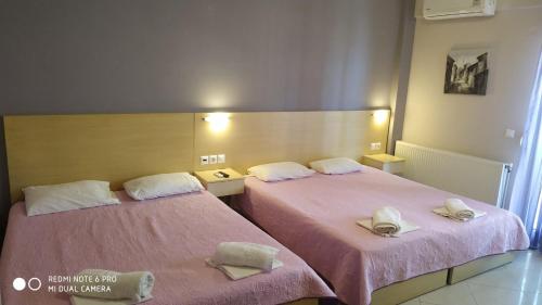 two beds in a room with pink sheets at Oniro Rooms & Suites in Leptokaria