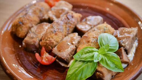 a plate of food with meat and vegetables and a green garnishment at Central Inn in Zlatibor