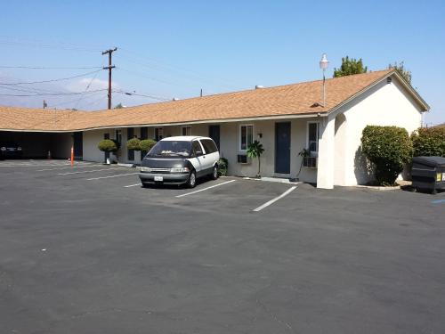 a car parked in a parking lot in front of a building at New Kansan Motel in Rancho Cucamonga
