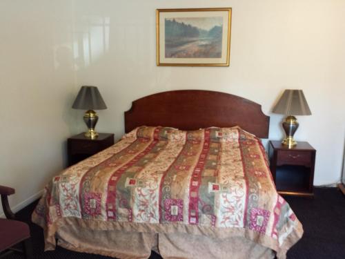 a bedroom with a bed and two night stands with lamps at New Kansan Motel in Rancho Cucamonga