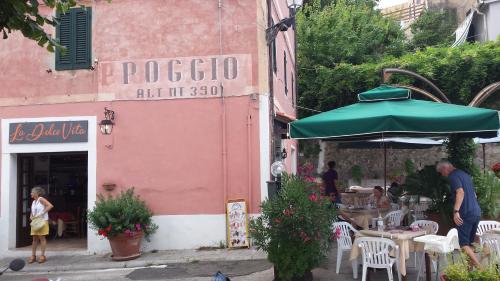 a group of people standing outside a restaurant with a green umbrella at La Casalina dell'Elba in Marciana