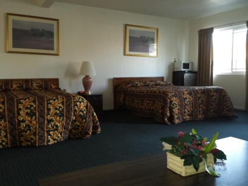a hotel room with two beds and a table at New Kansan Motel in Rancho Cucamonga