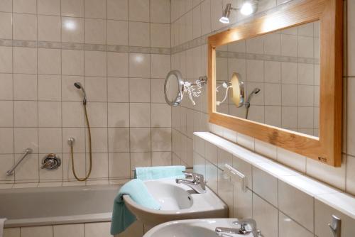 a bathroom with a sink and a mirror and a tub at Ferienhaus/Ferienwohnung BeeHappy in Aichstetten