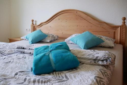 a bed with two blue pillows on top of it at Ferienhaus/Ferienwohnung BeeHappy in Aichstetten