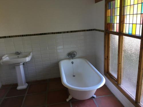 La salle de bains est pourvue d'une baignoire et d'un lavabo. dans l'établissement Trengwainton House, à Hogsback